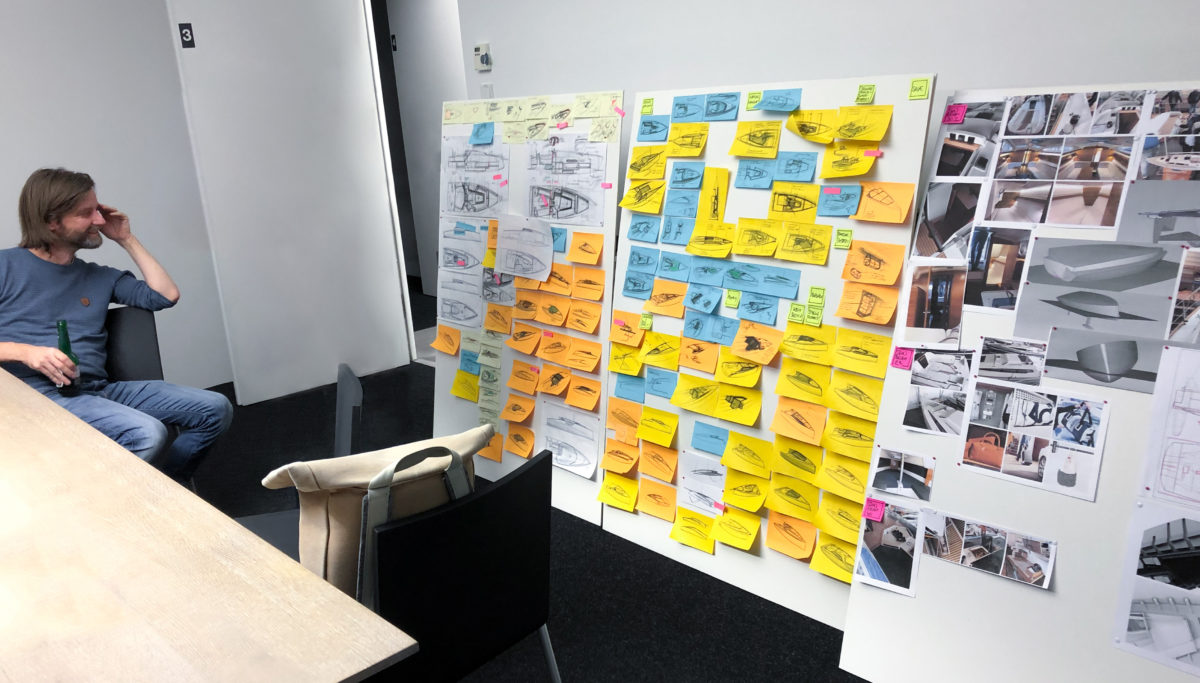 Man looking at Post it sketches and renders on a board in a meeting room for Sunbeam 32.1 boat designed by KISKA