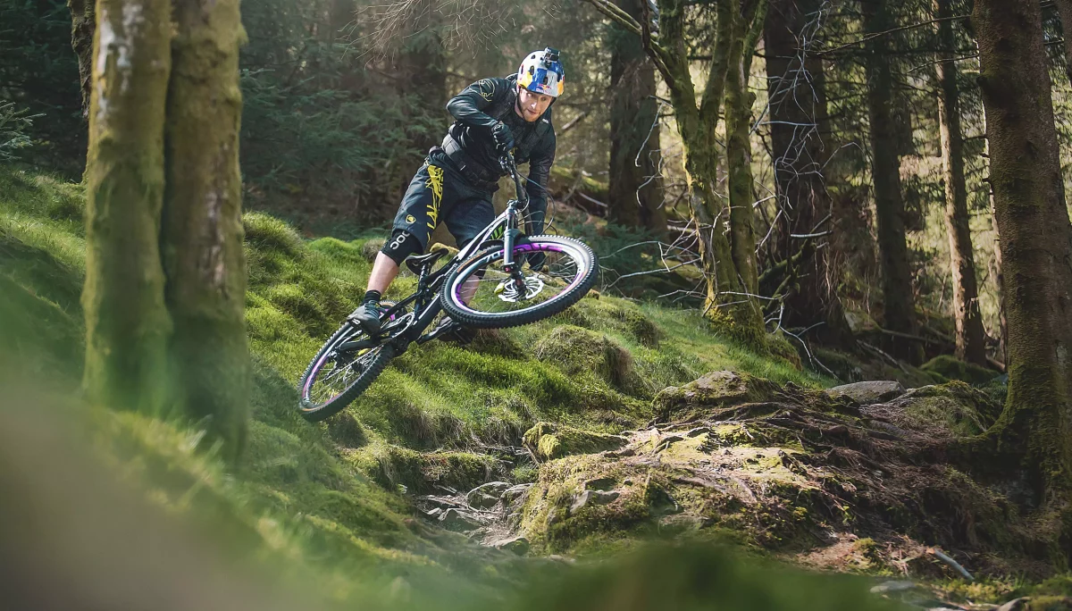Danny Macaskill on bike jumping in forest Landscape crop