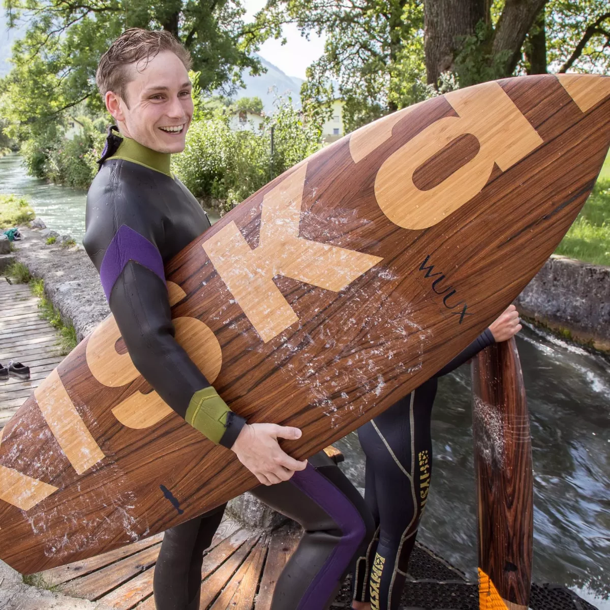 KISKA transportation designer holding the KISKA surfboard at the Salzburg Almkanal