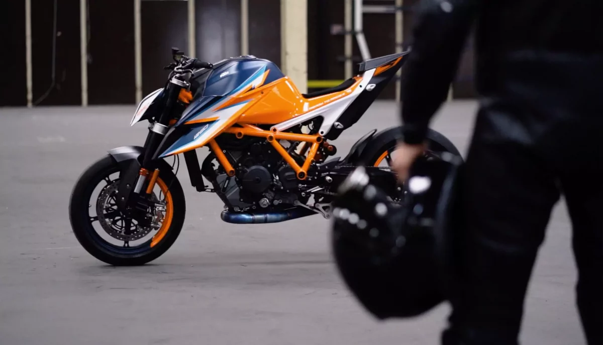 Side view of KTM 1290 Super Duke R in a warehouse with motorcycle rider looking at it
